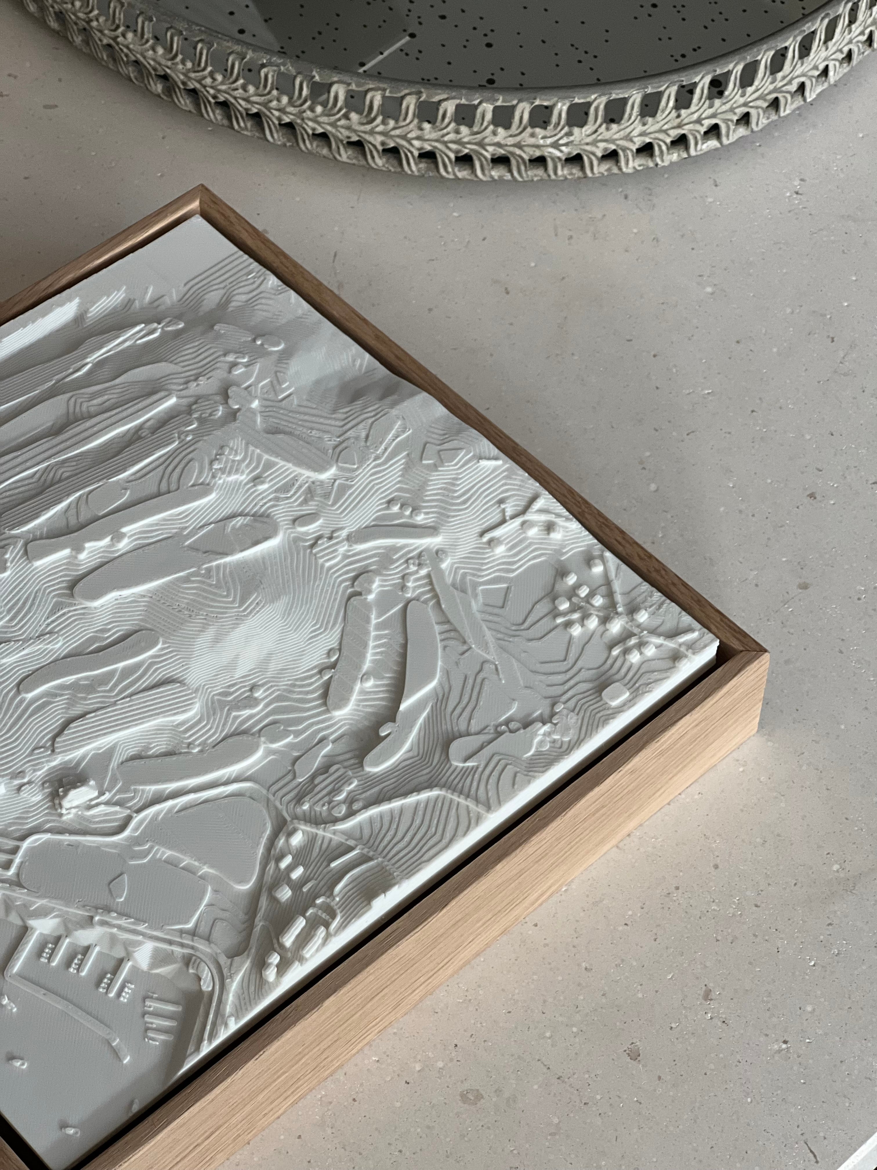 Modern 3D city map wall art in a wooden frame on a light stone surface