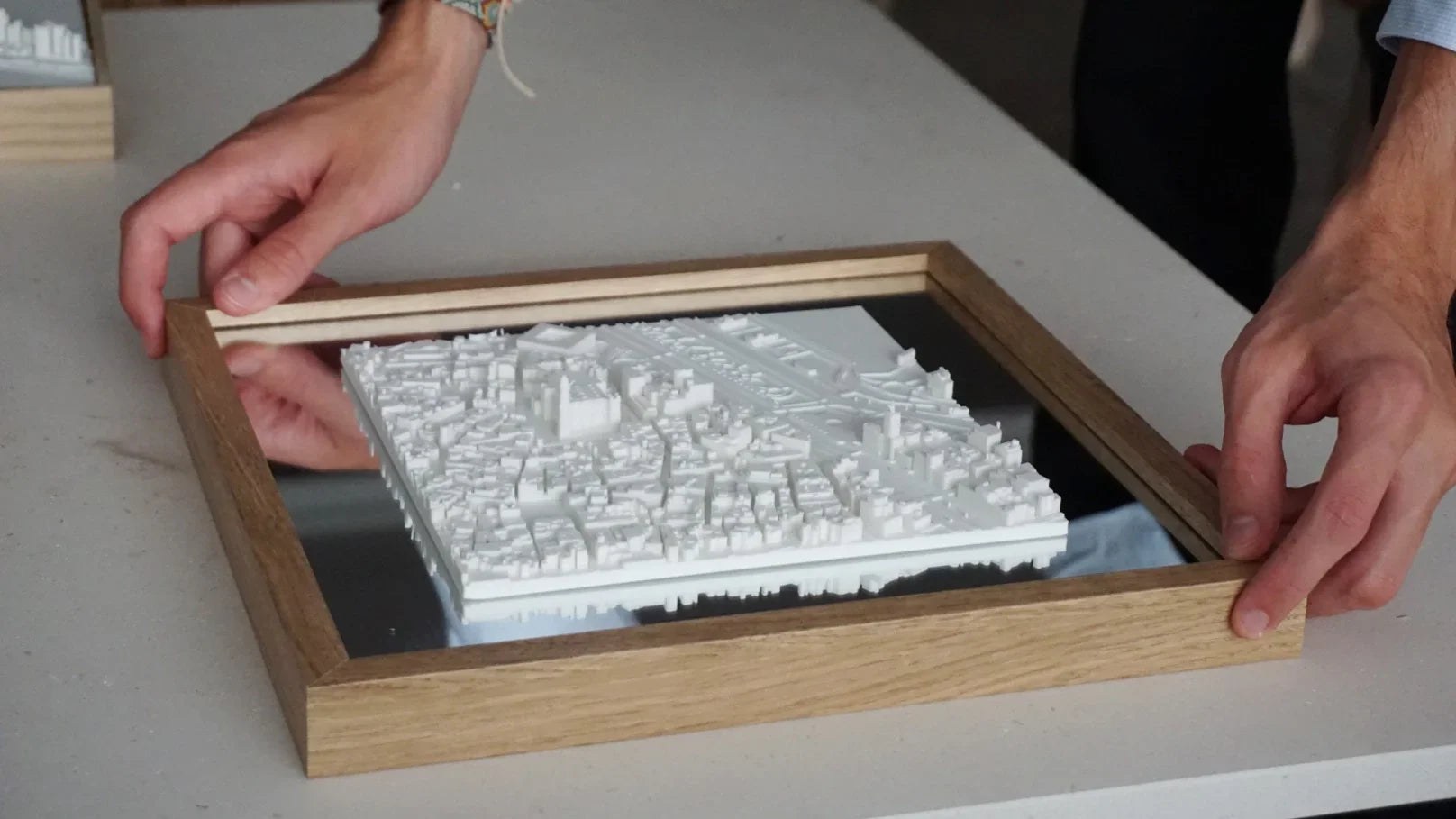 Hands holding framed 3D city map, modern wall decor for travelers and home decoration