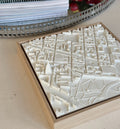 3D city map wall art with detailed white buildings and streets in a wooden frame