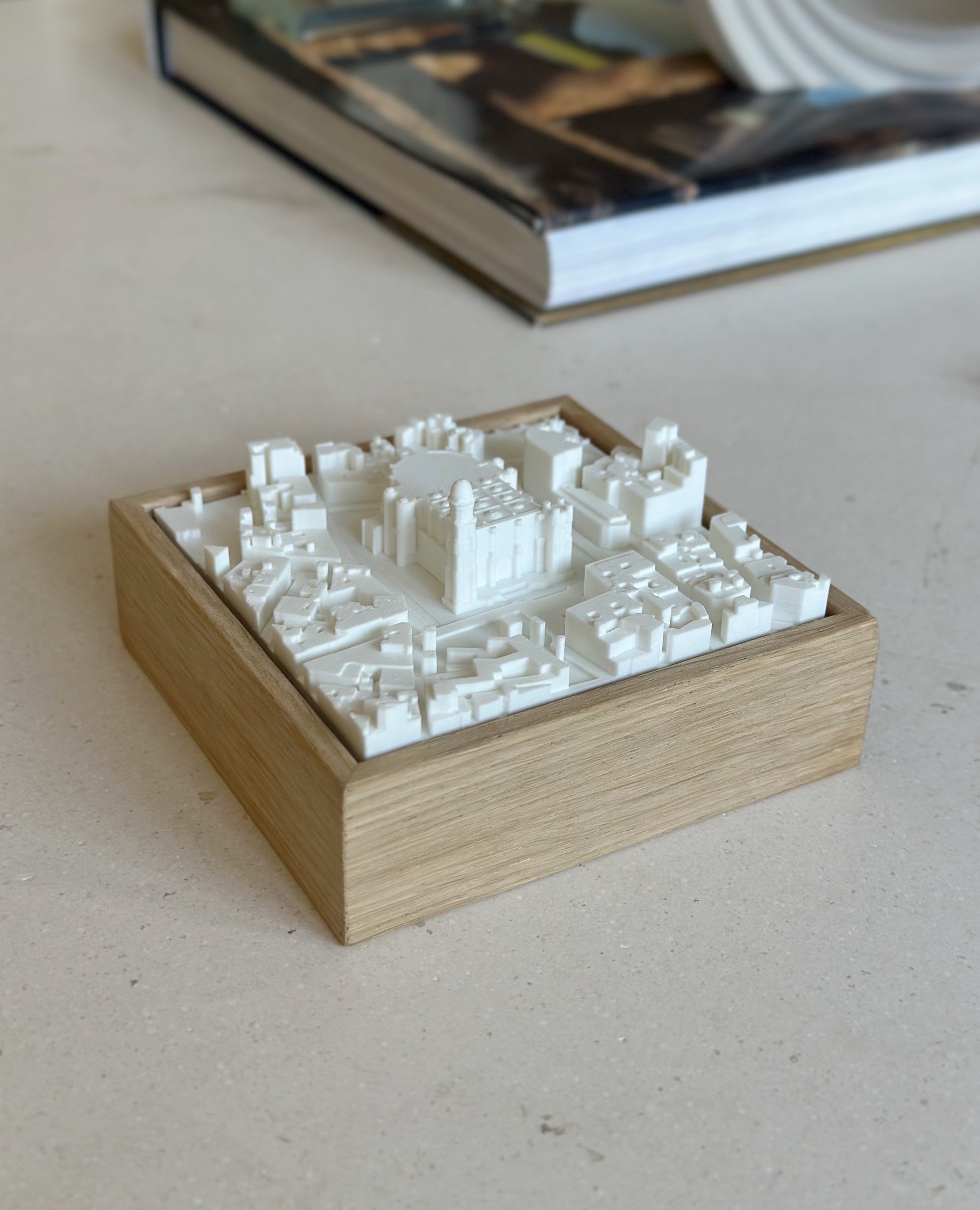 3D city map wall art in a wooden frame on a light table, decorative urban model.