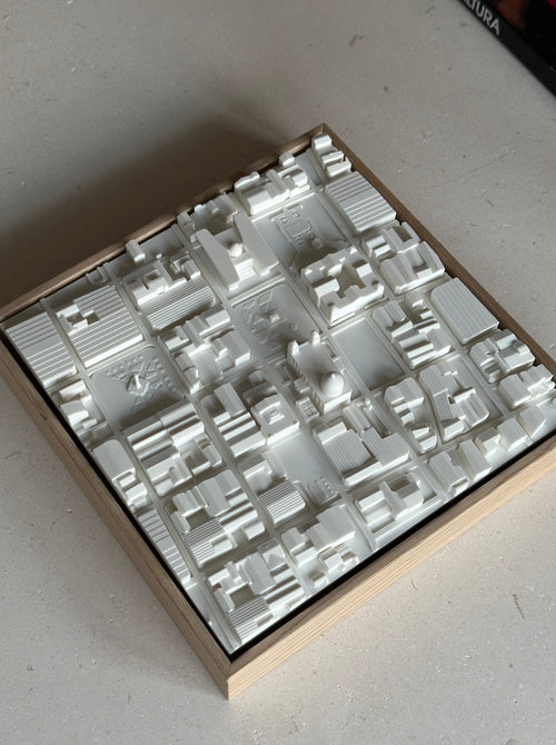 3D city map wall art in a wooden frame, featuring detailed miniature buildings.