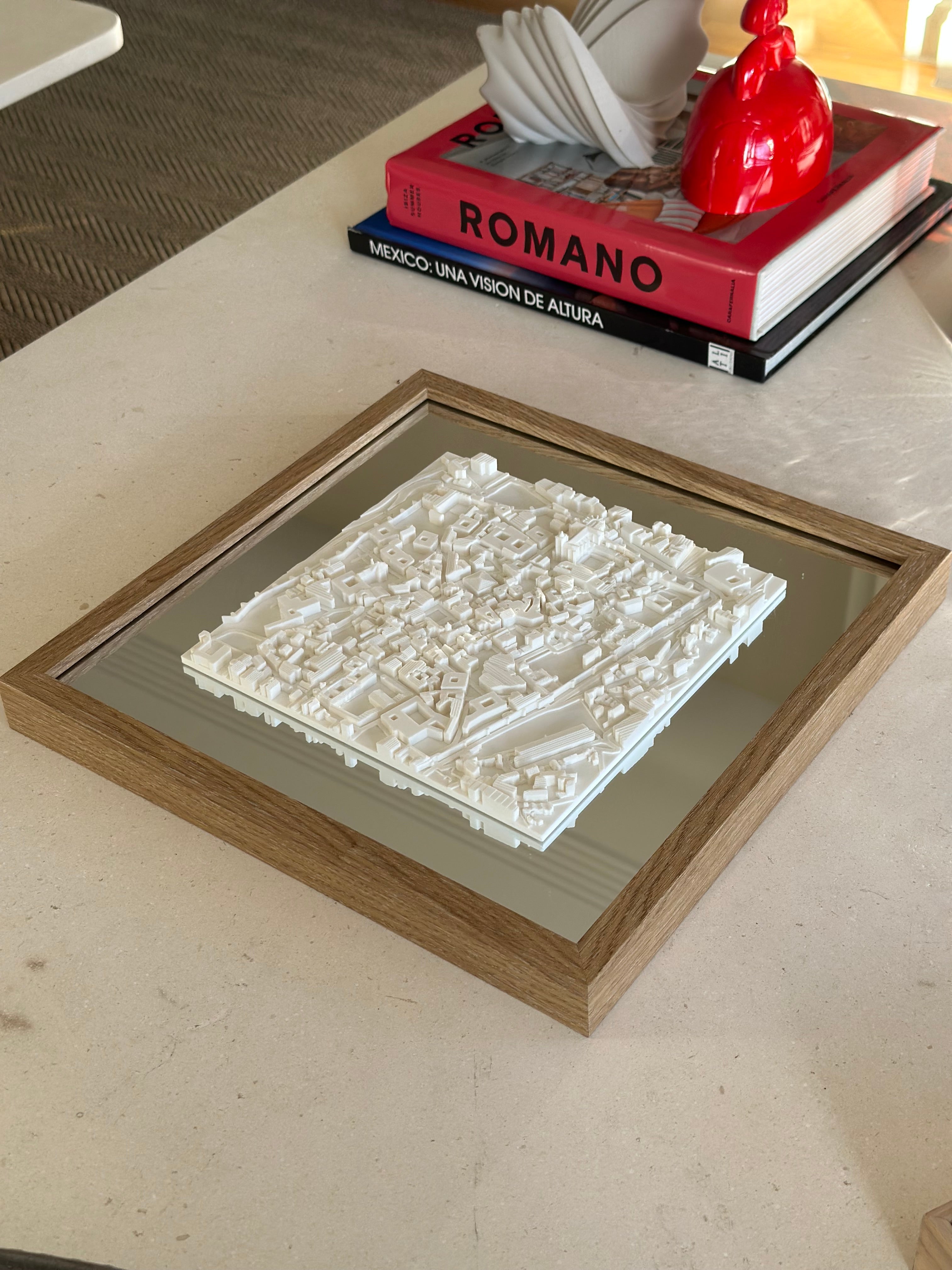 3D city map wall art in wooden frame on modern coffee table, with decorative books and sculpture