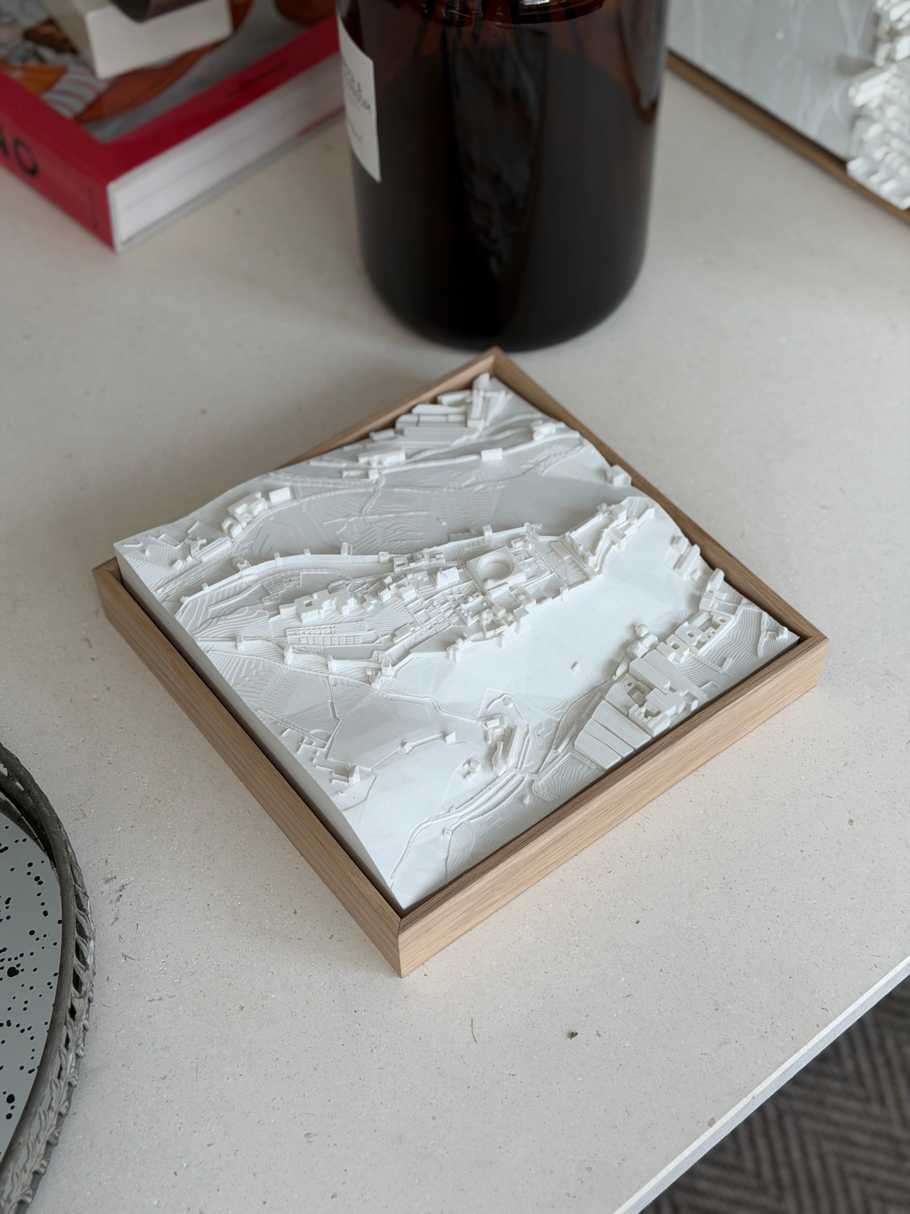 3D city map wall art in a wooden frame displayed on a modern tabletop
