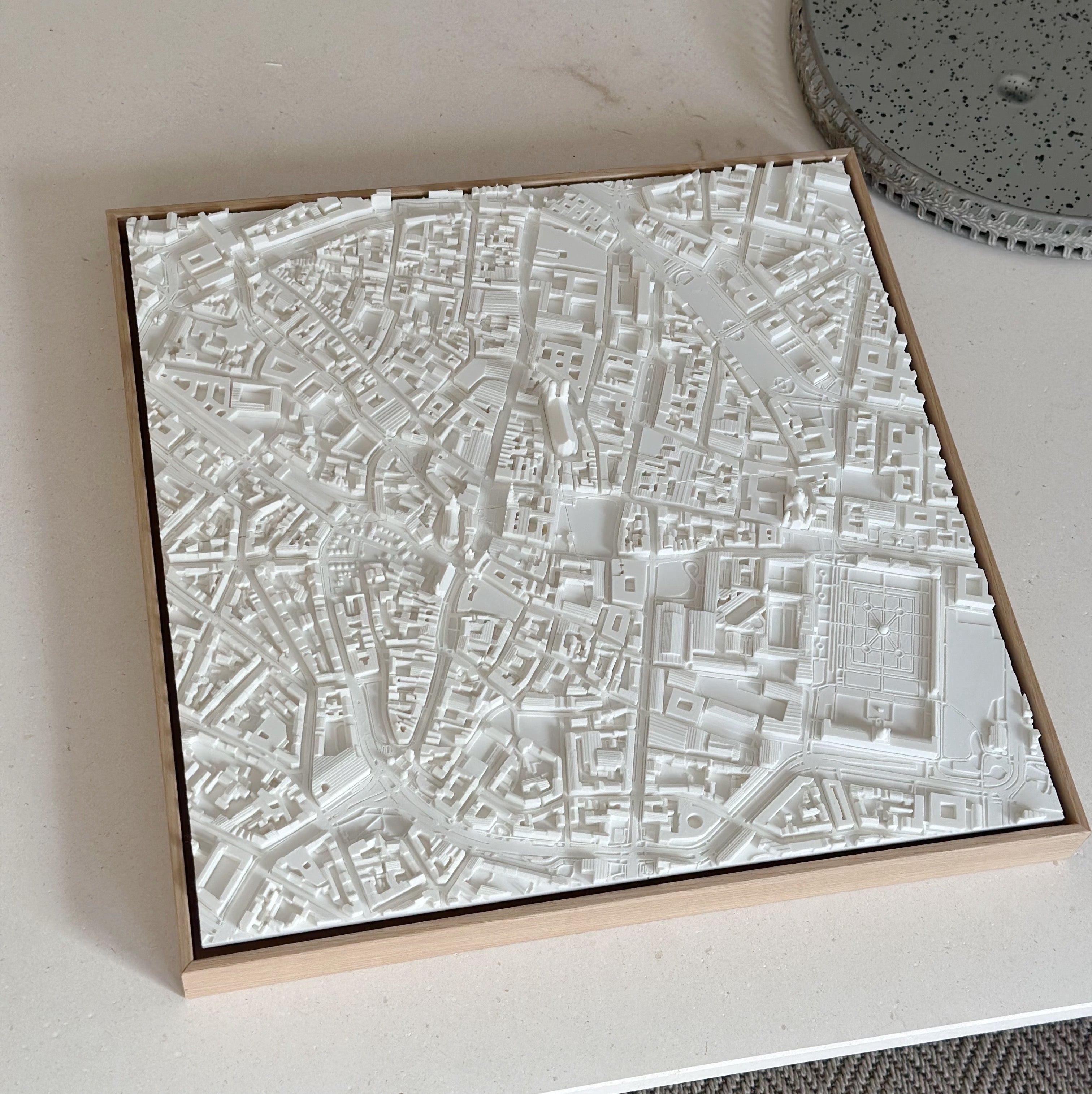 3D city map wall art decor in white, displayed on a table, modern urban topography