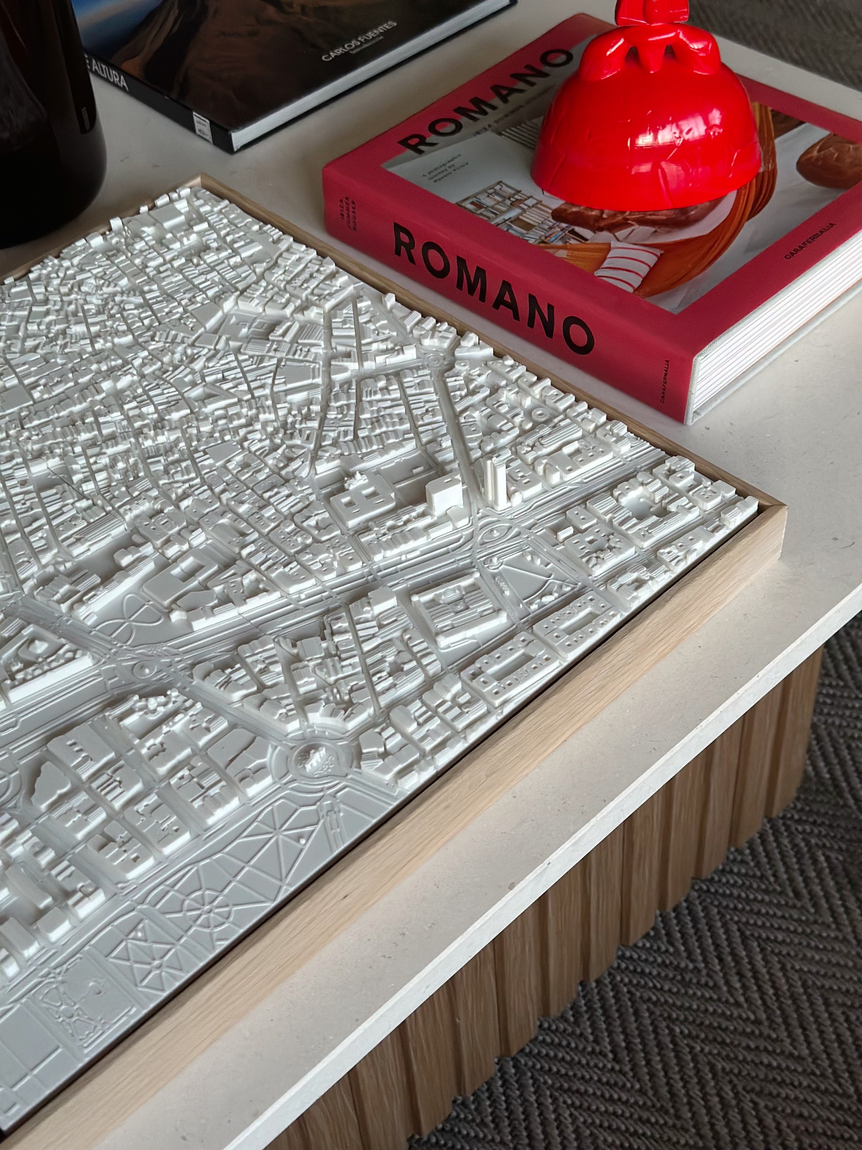 White 3D city map wall art on a modern coffee table with books and decor