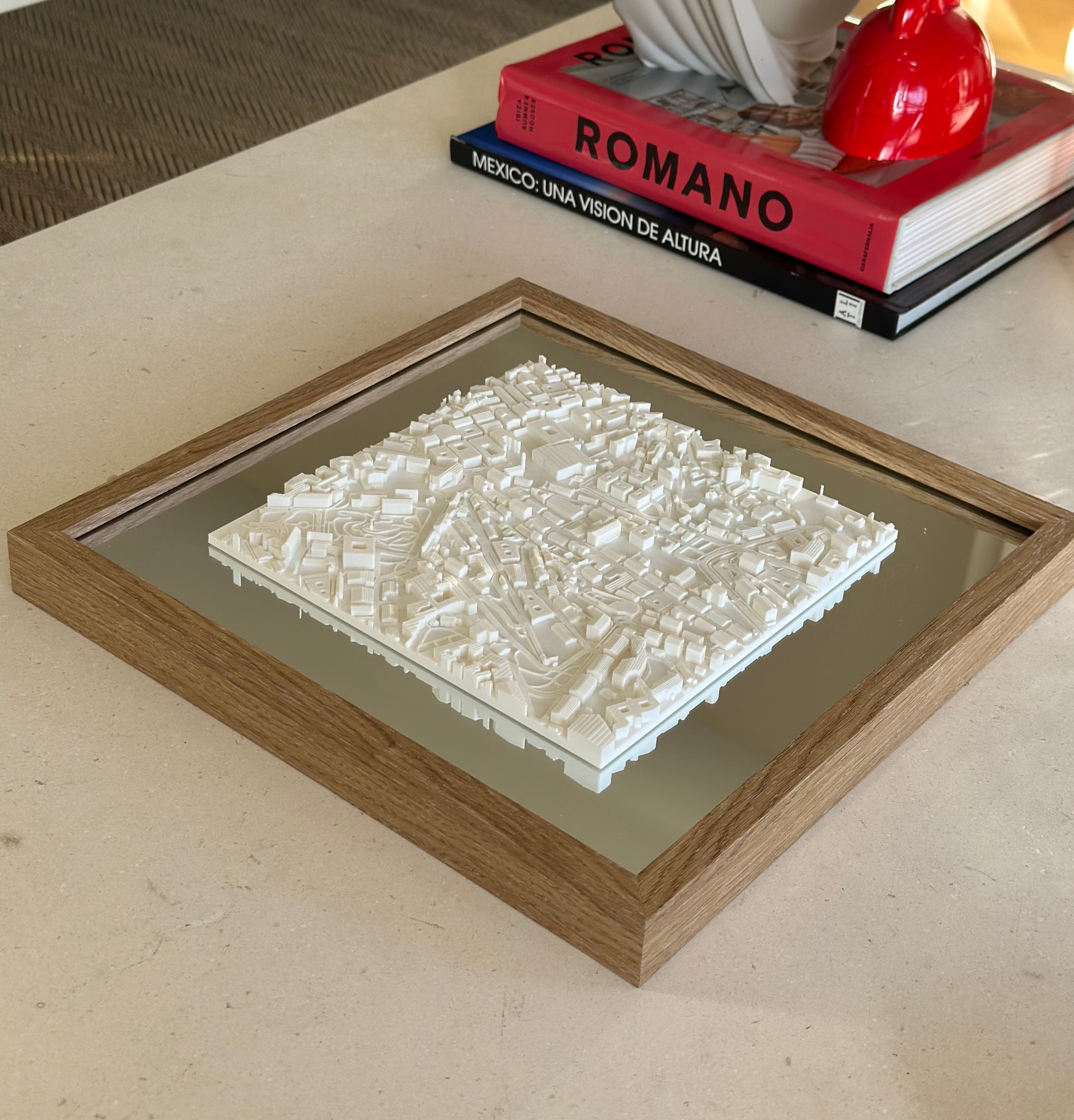 3D city map wall art in wooden frame on table with decorative books in background