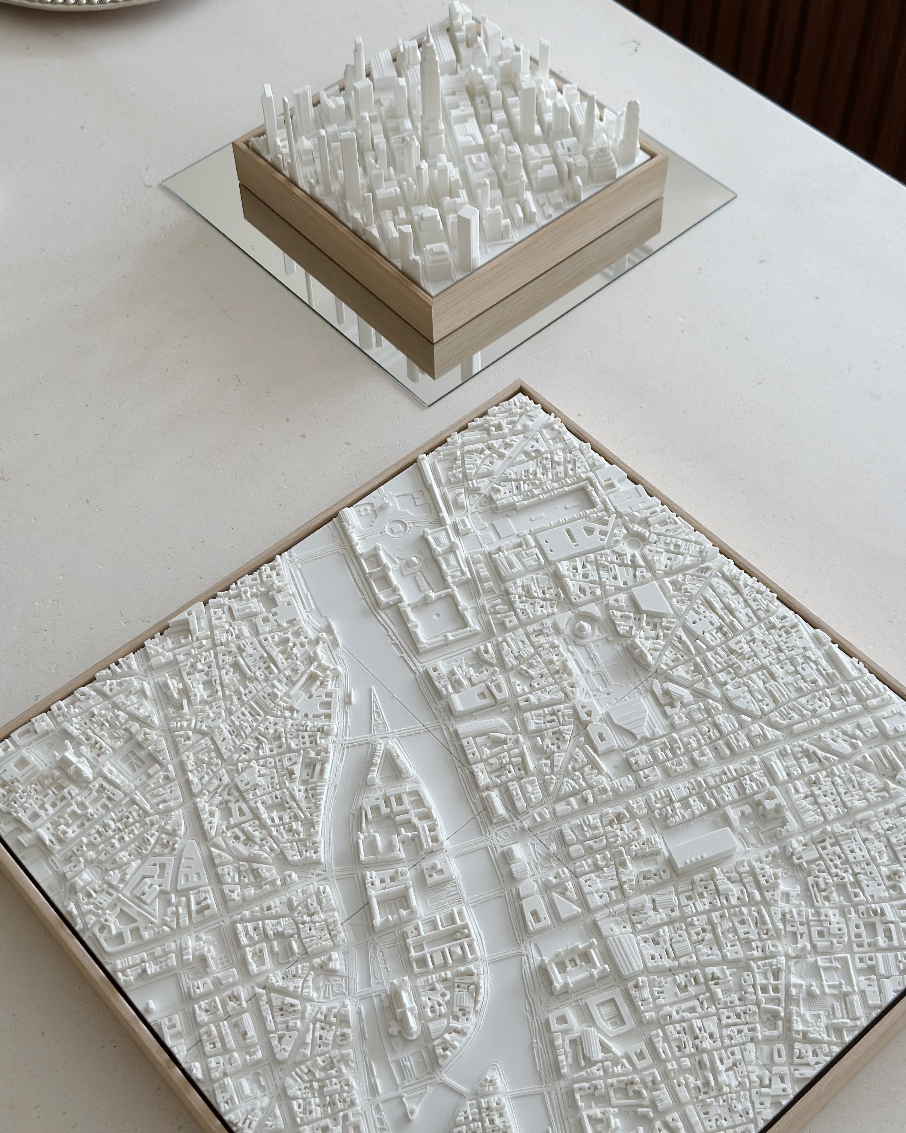 3D city map wall art models in white, featuring detailed urban landscapes on a tabletop.