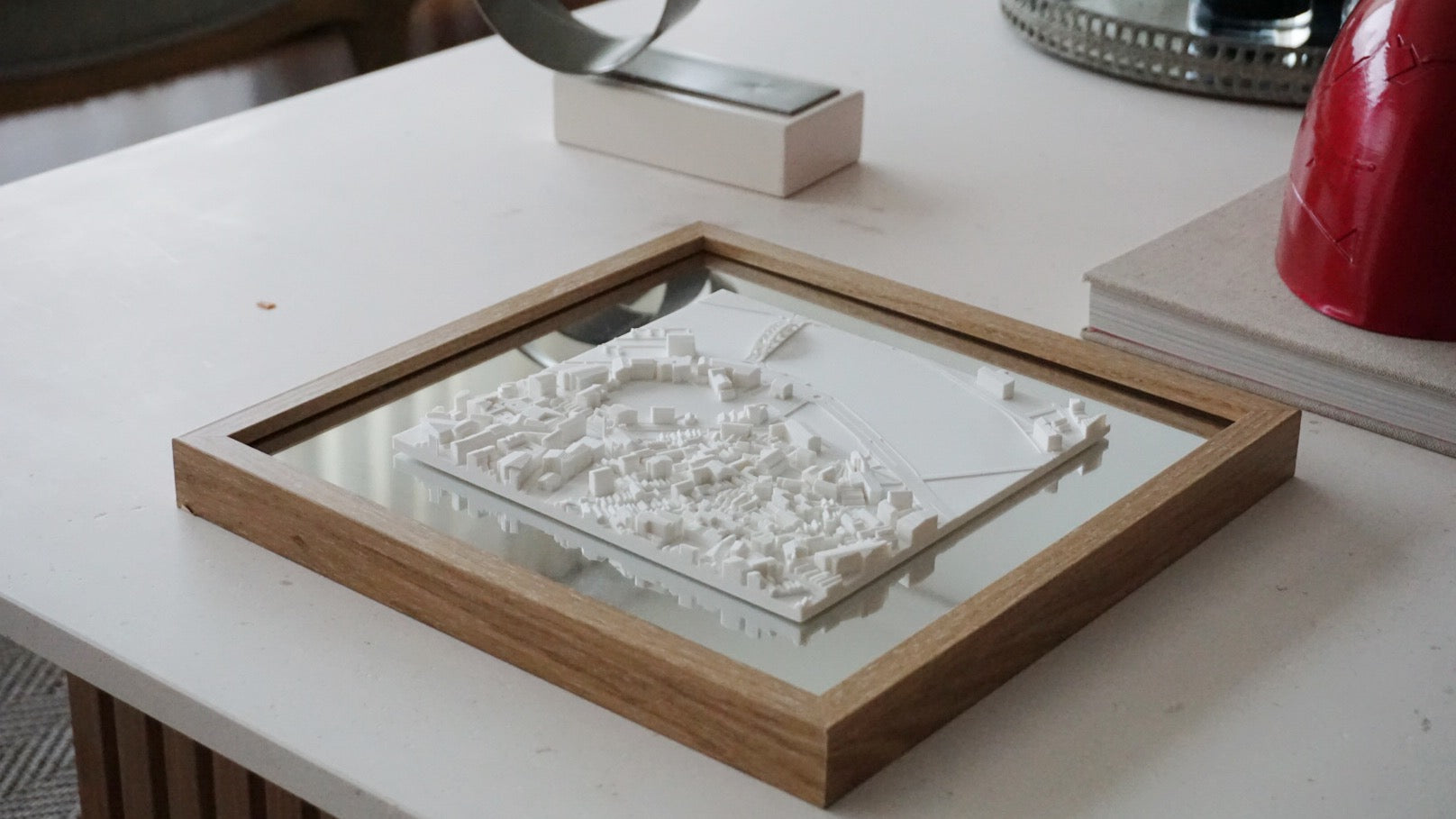 Framed 3D city map art in white, displayed on a modern coffee table