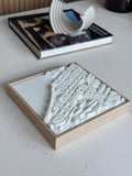 3D city map wall art in a wooden frame on a modern tabletop, decorative book and sculpture nearby