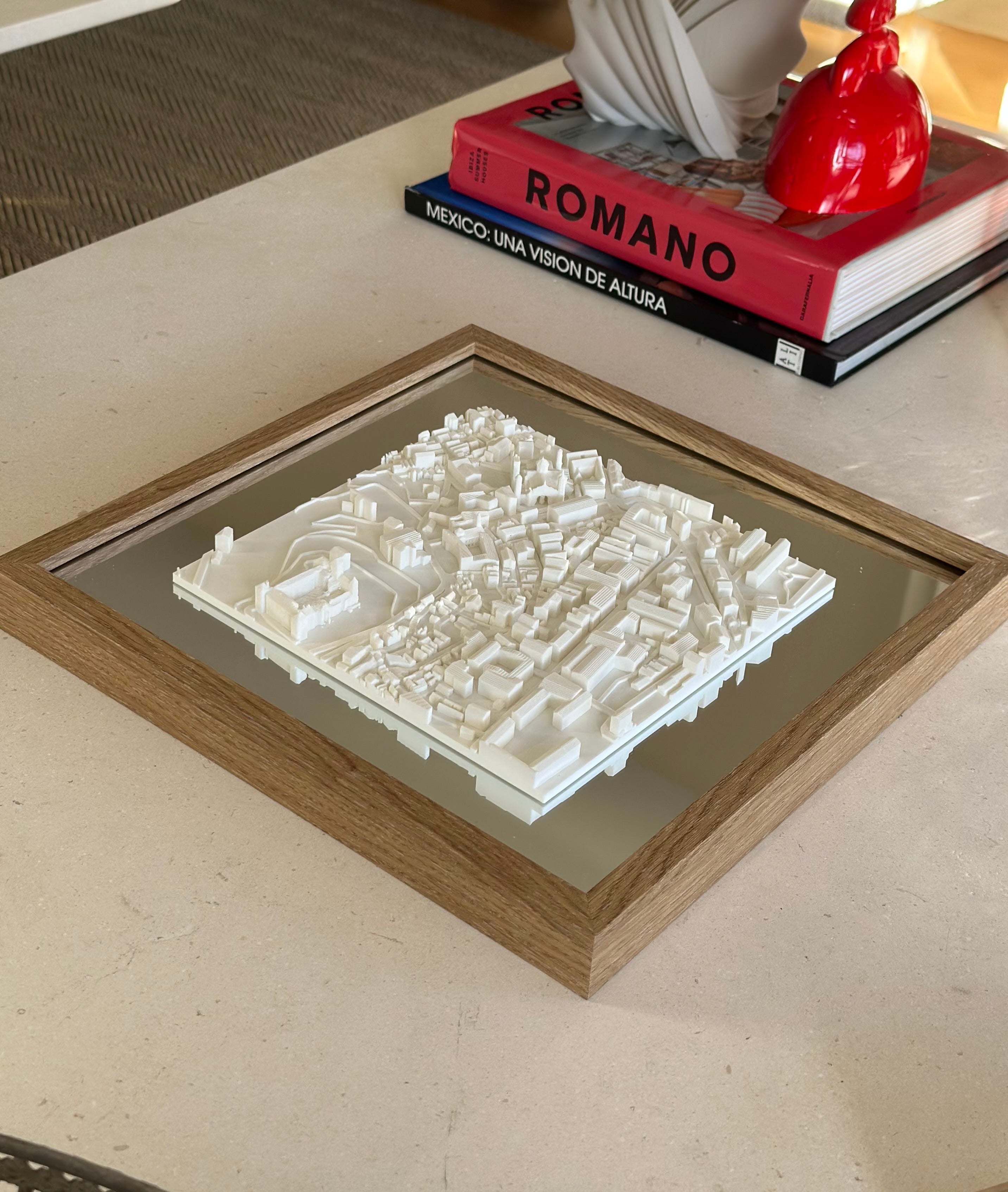 Framed 3D city map wall art in white on a coffee table, with modern decor and books nearby.