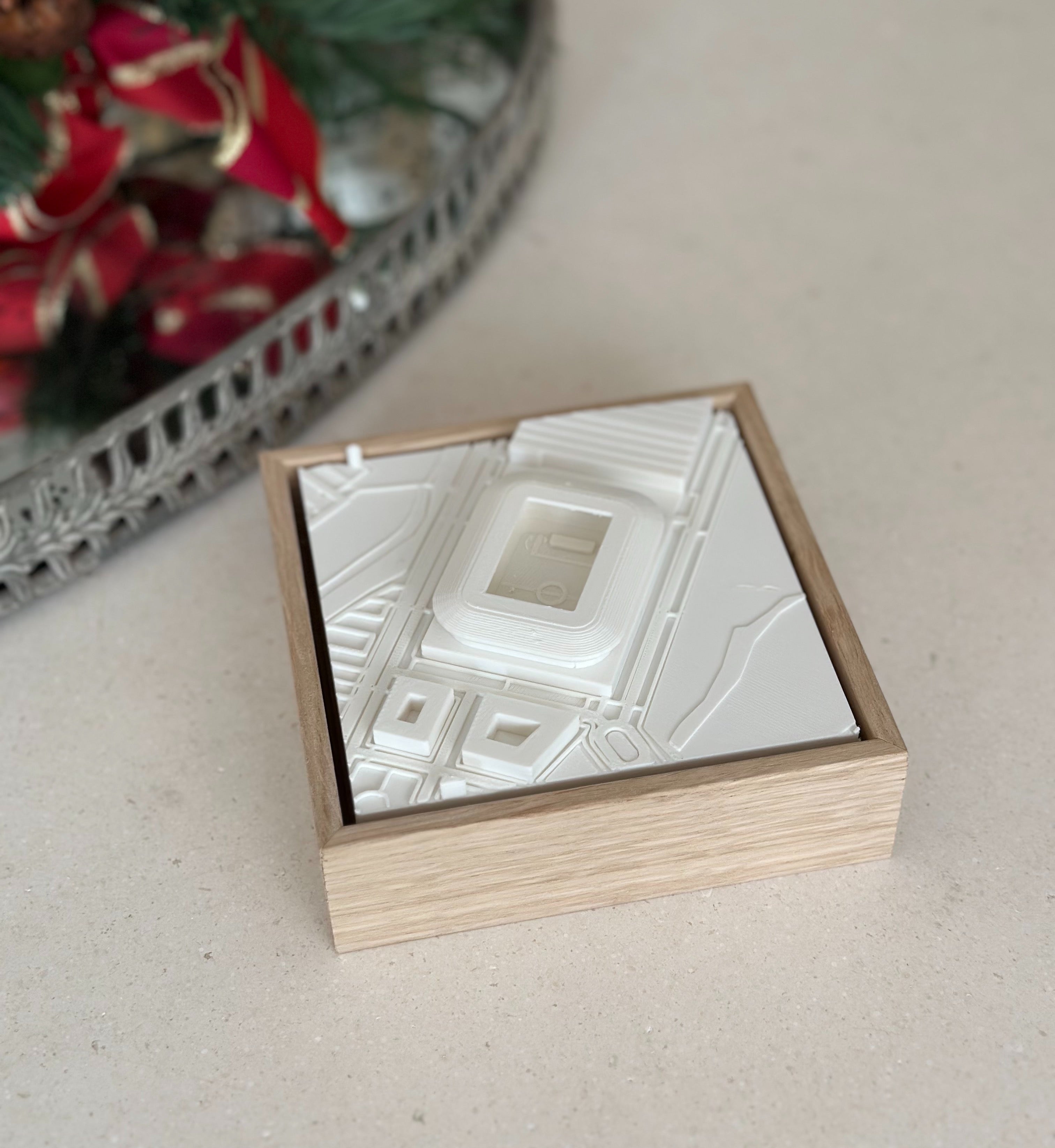 3D city map wall art in wooden frame on a table, with holiday decor in background
