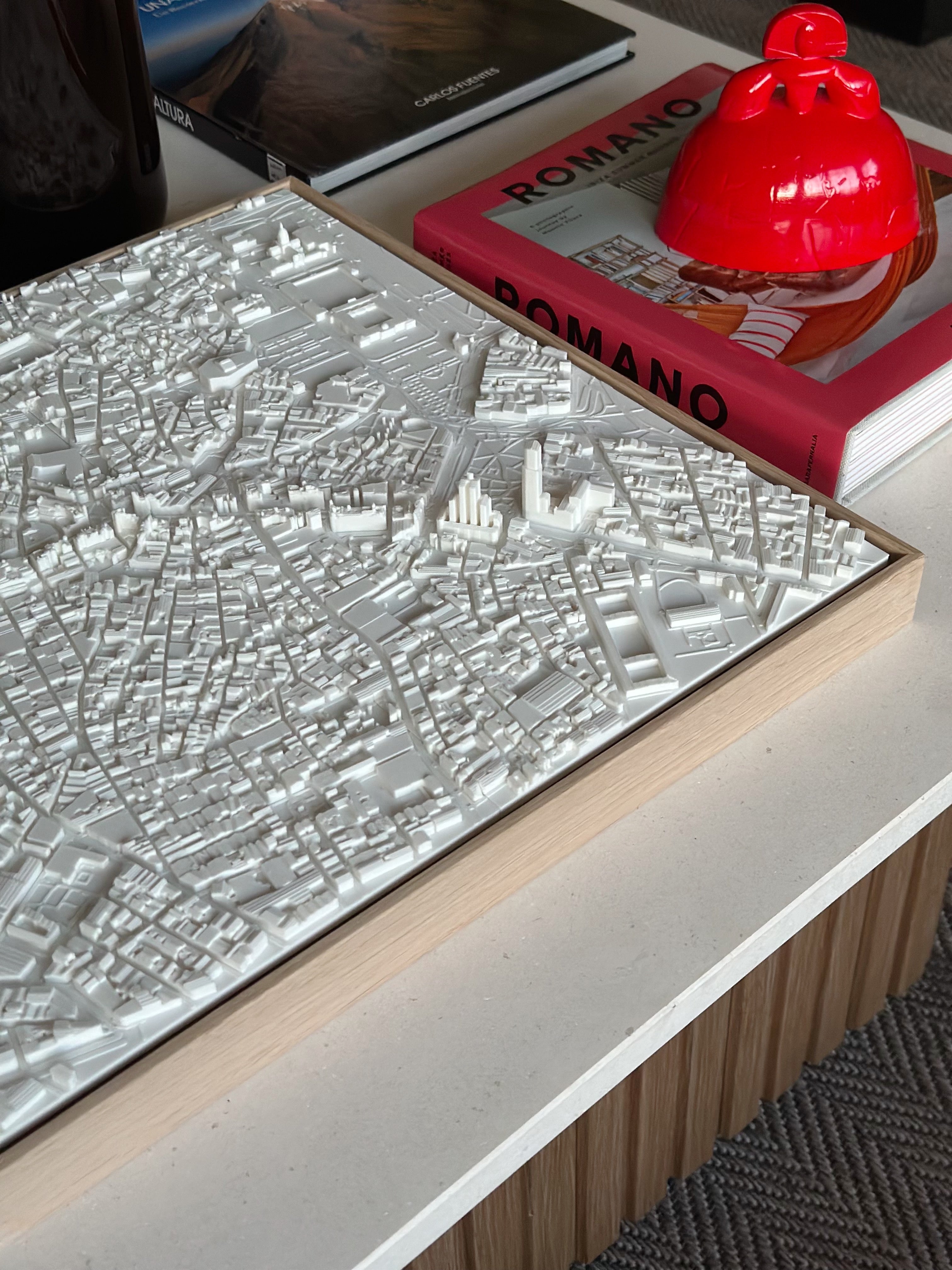 3D city map wall art on table with books and decorative red object