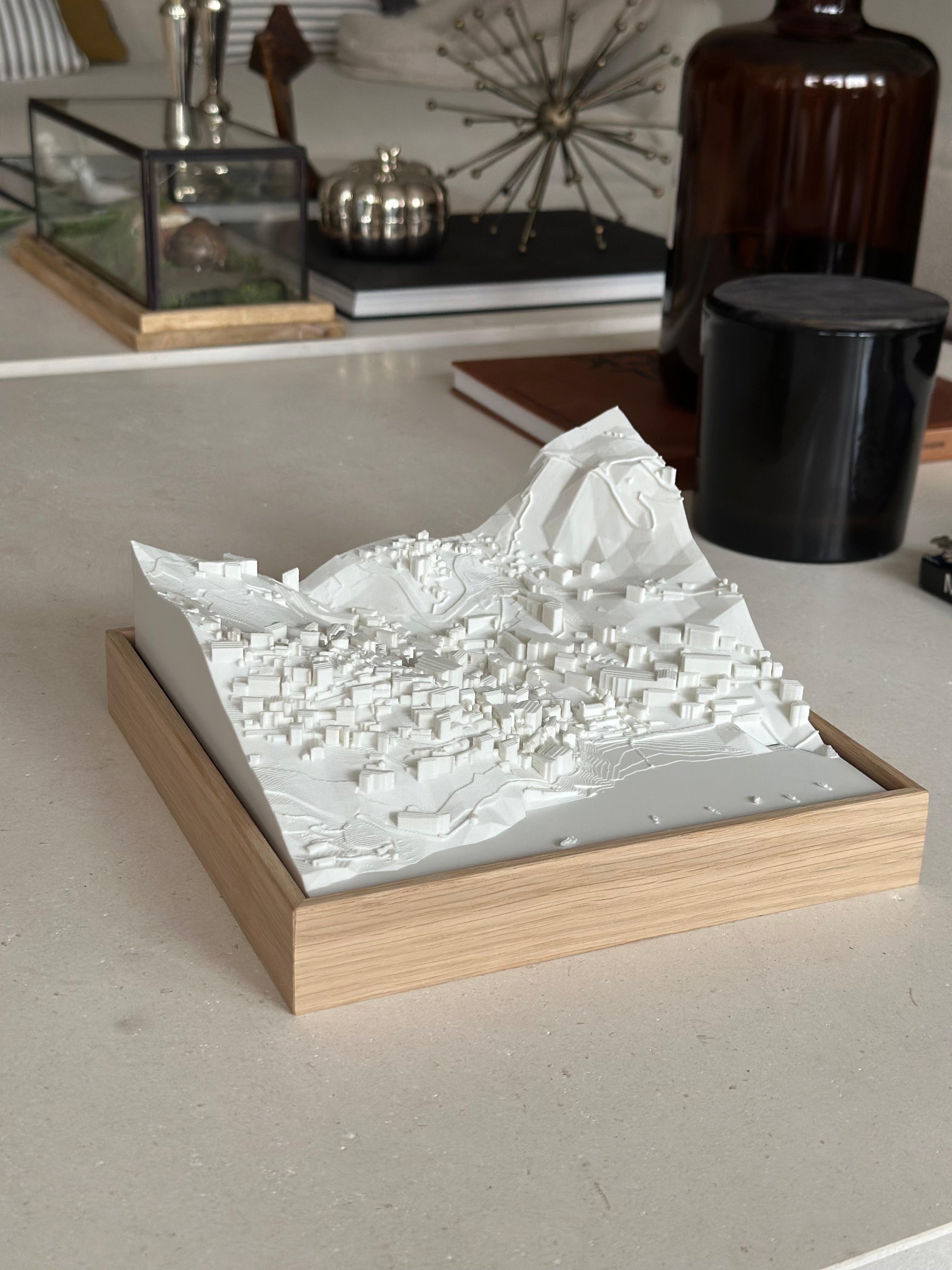 3D city map sculpture in a wooden frame on a modern decorated table
