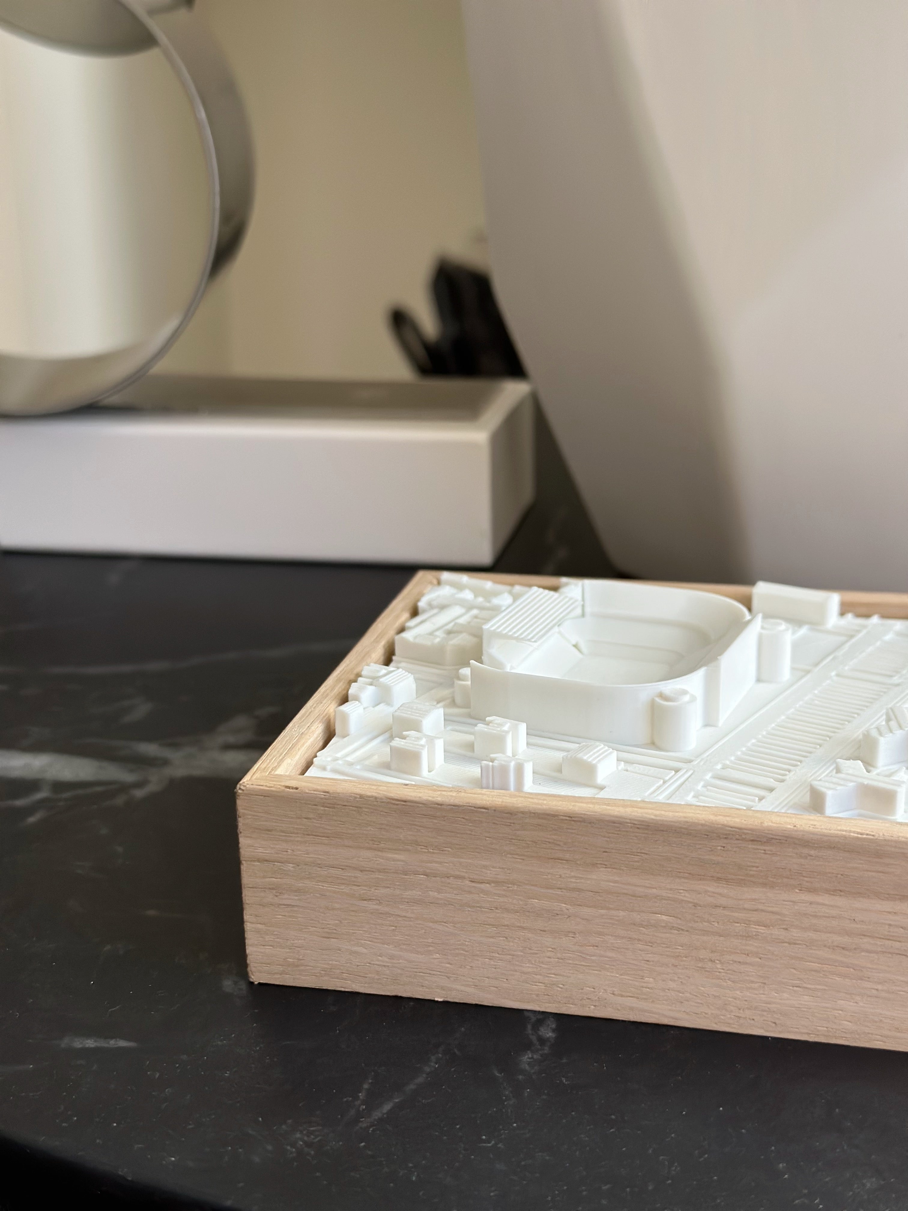 3D city map wall art in a wooden frame on a black marble surface