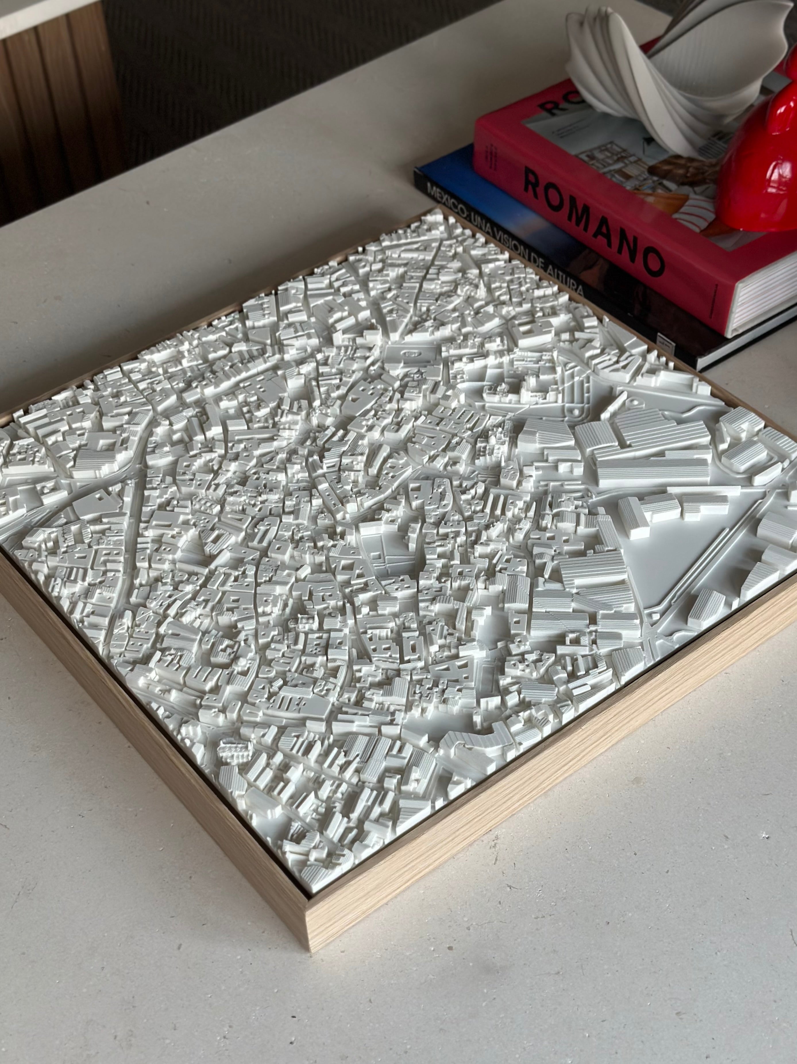 3D city map wall art in white on a wooden frame, modern decor on a table with books