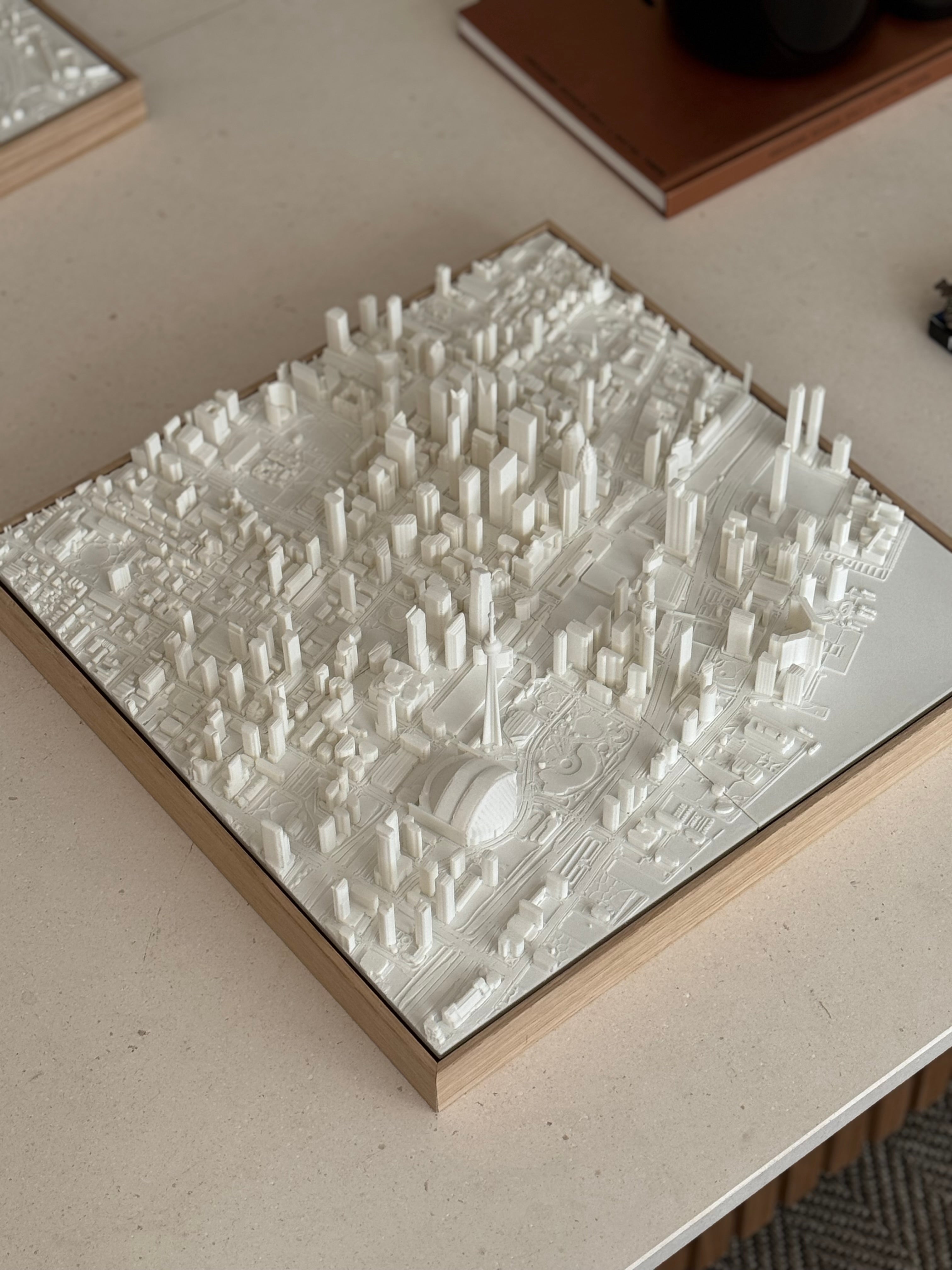 3D city map wall art with detailed white buildings and streets on a wooden frame, decorative piece