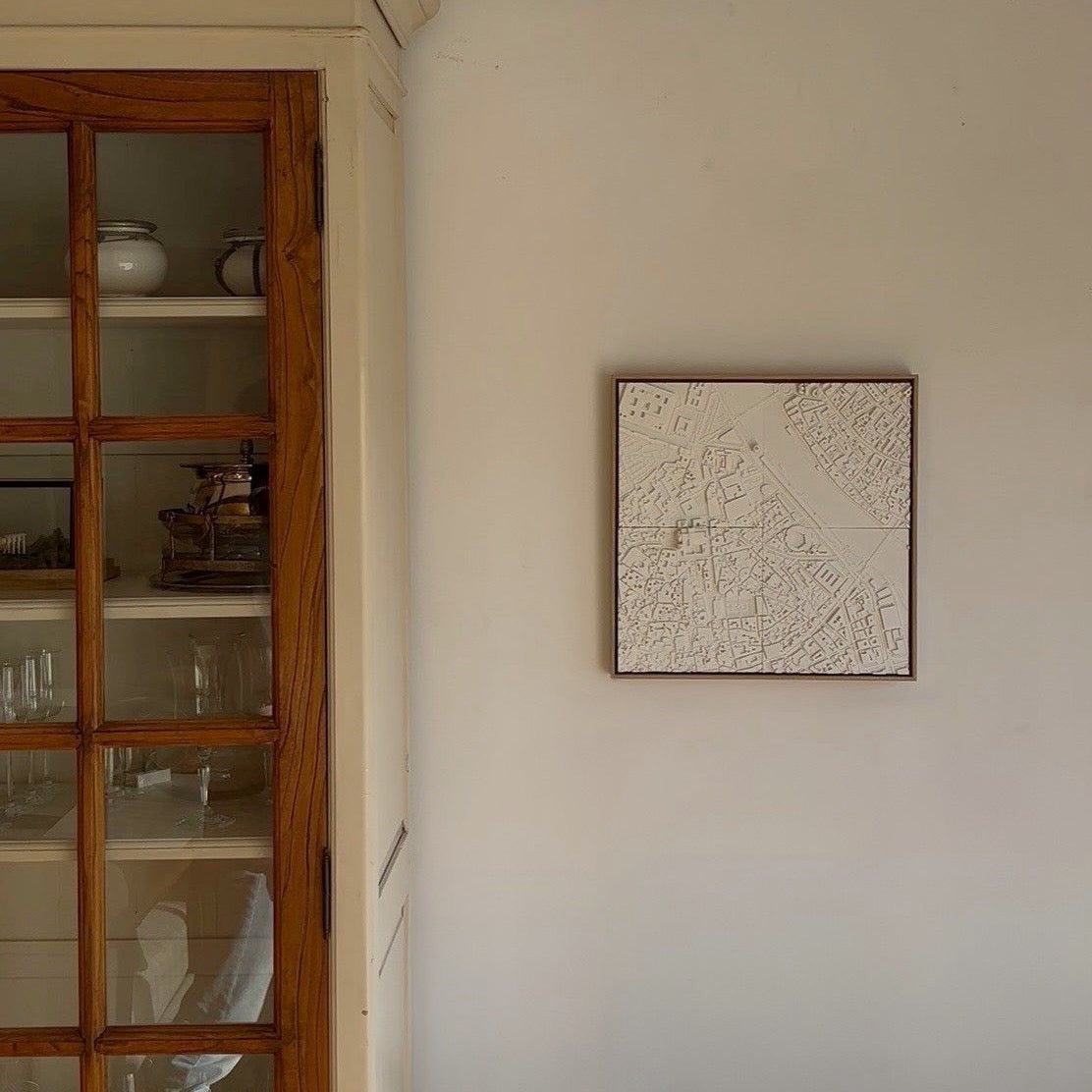 Modern living space with a 3D city map wall art hanging beside a wooden glass cabinet