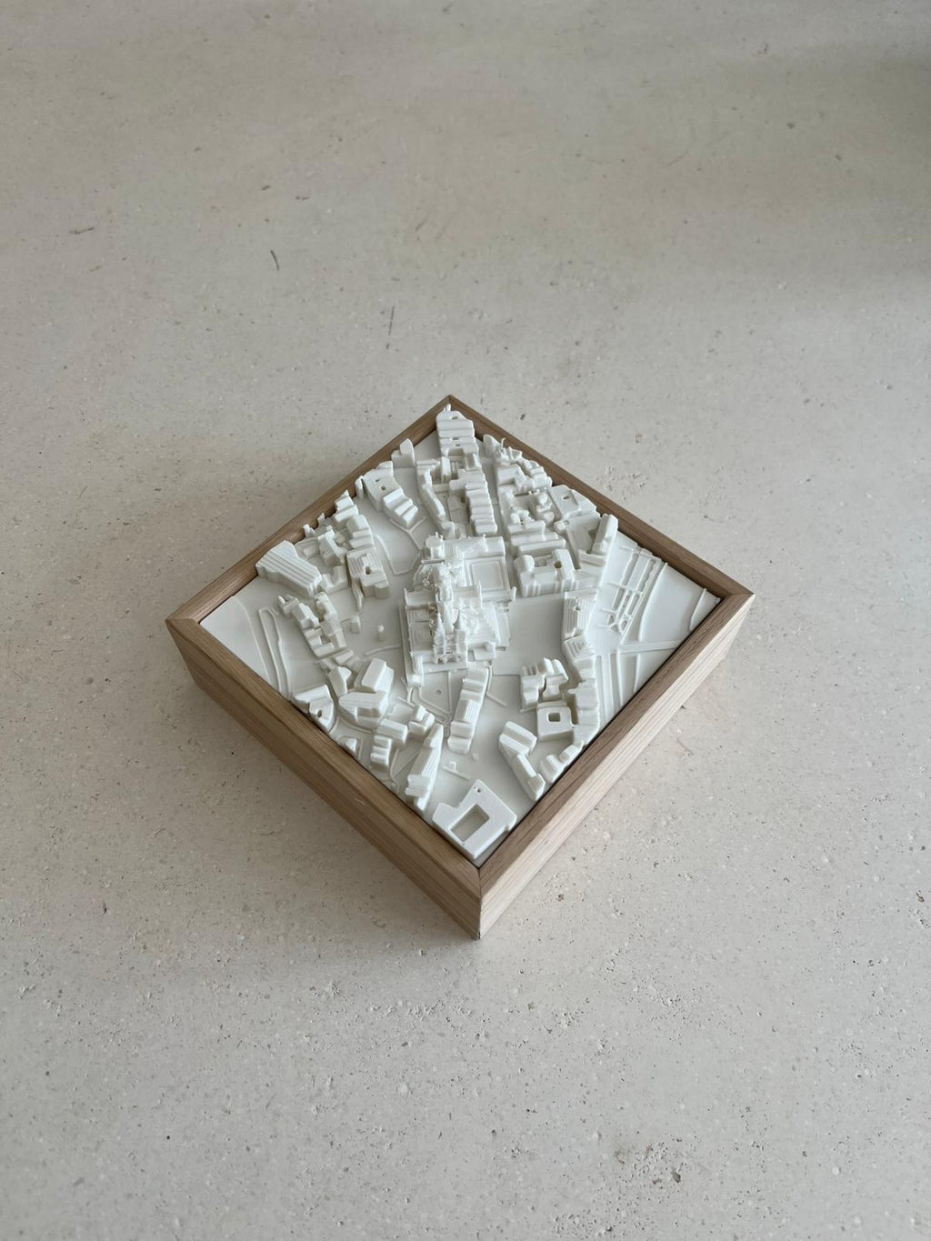 3D city map art in a wooden frame, minimalist decor piece on a light surface