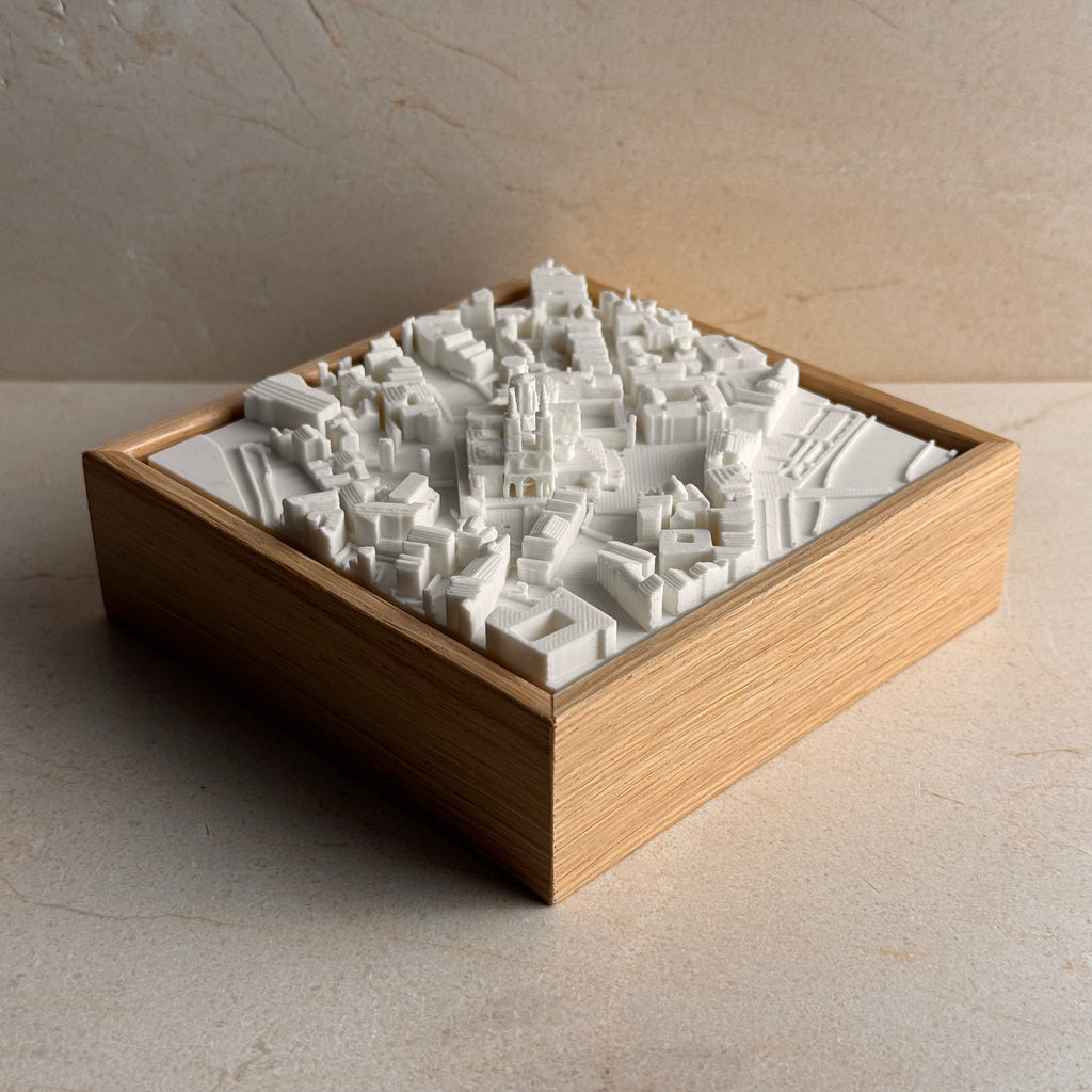 3D city map sculpture in white, displayed in a wooden frame, decorative wall art