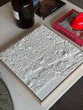 3D city map wall art in white on coffee table with books and decor around it