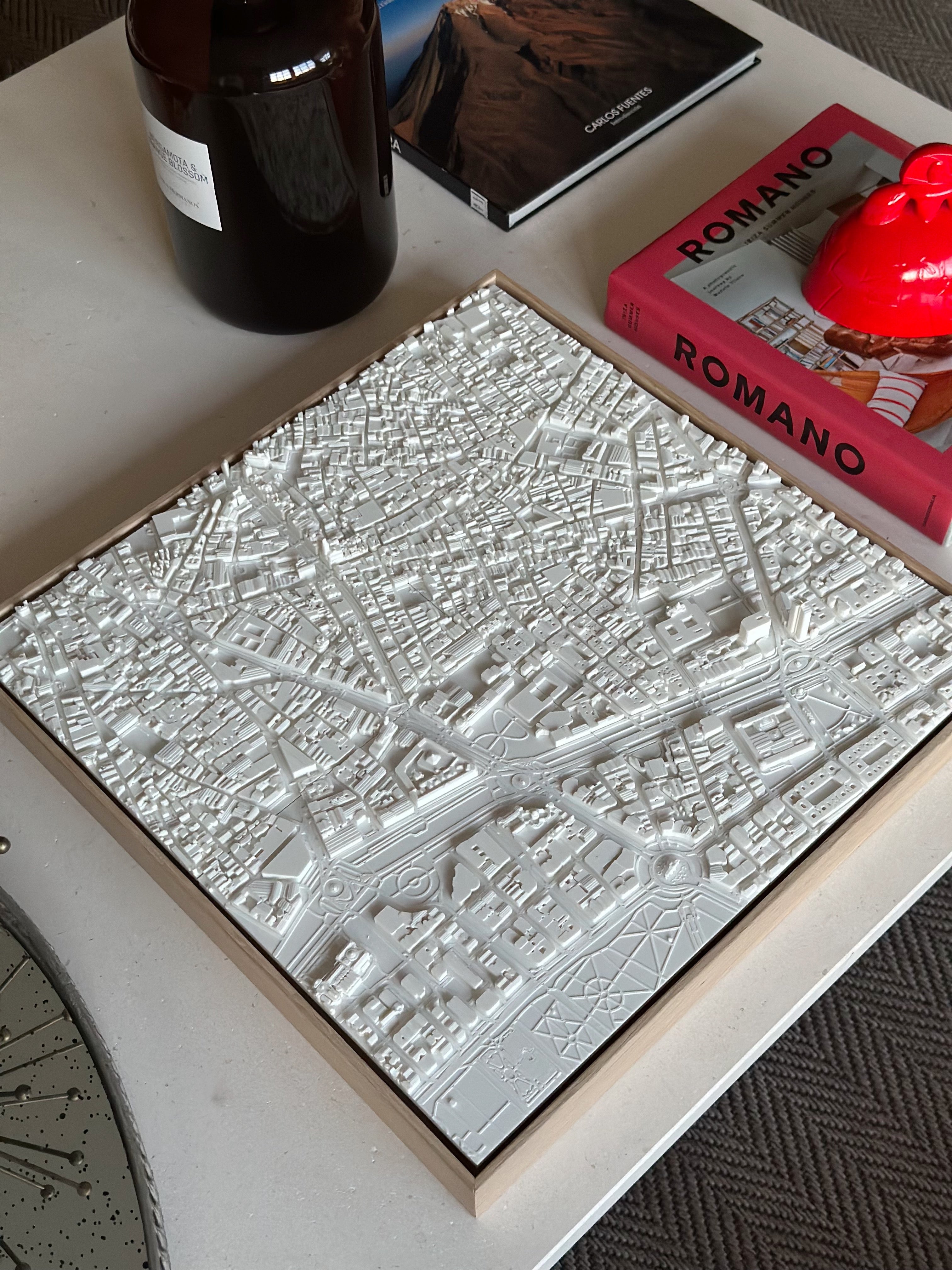 3D city map wall art in white on coffee table with books and decor around it