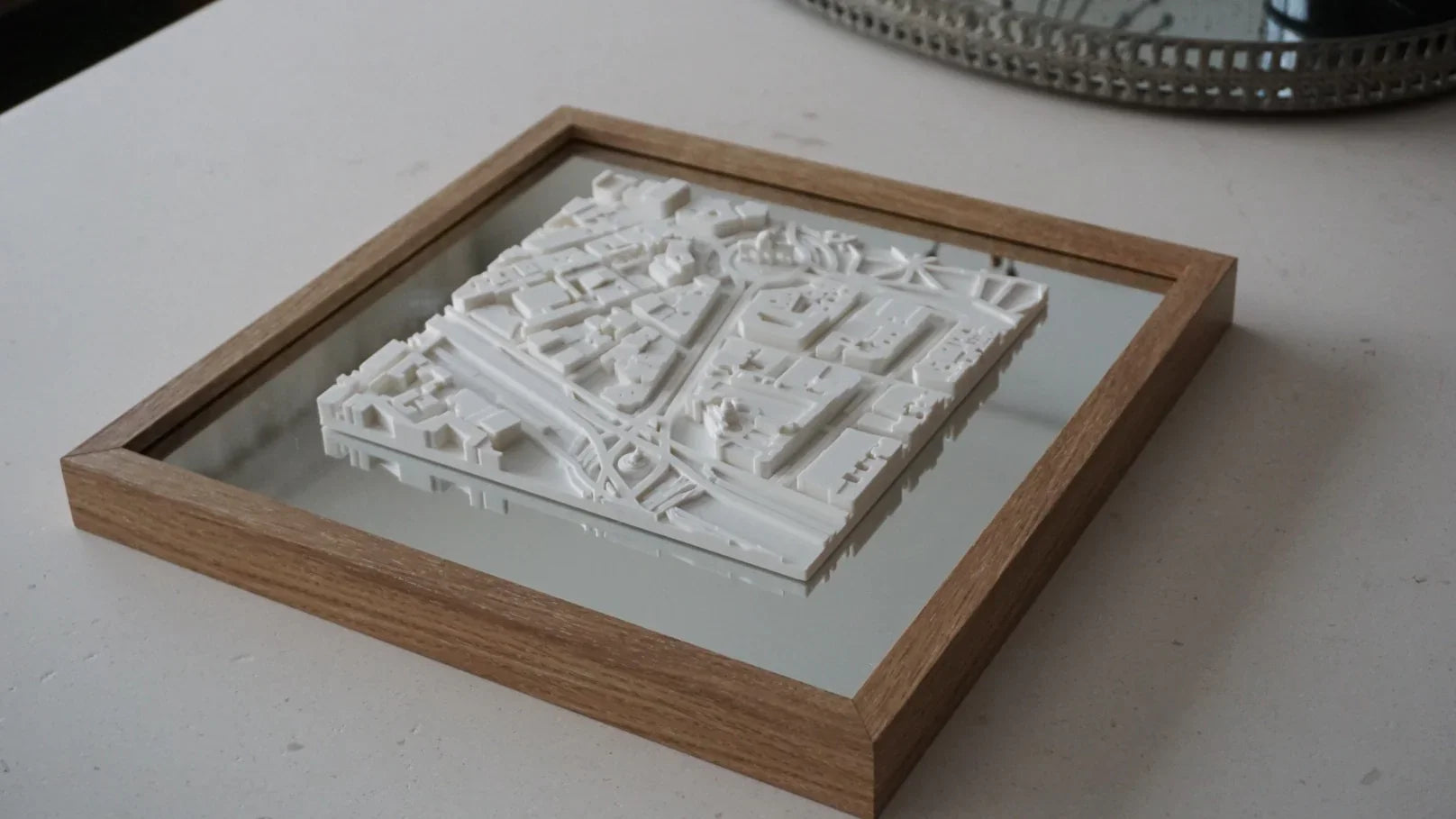 3D city map wall art in a wooden frame on a white surface, modern decor accent.