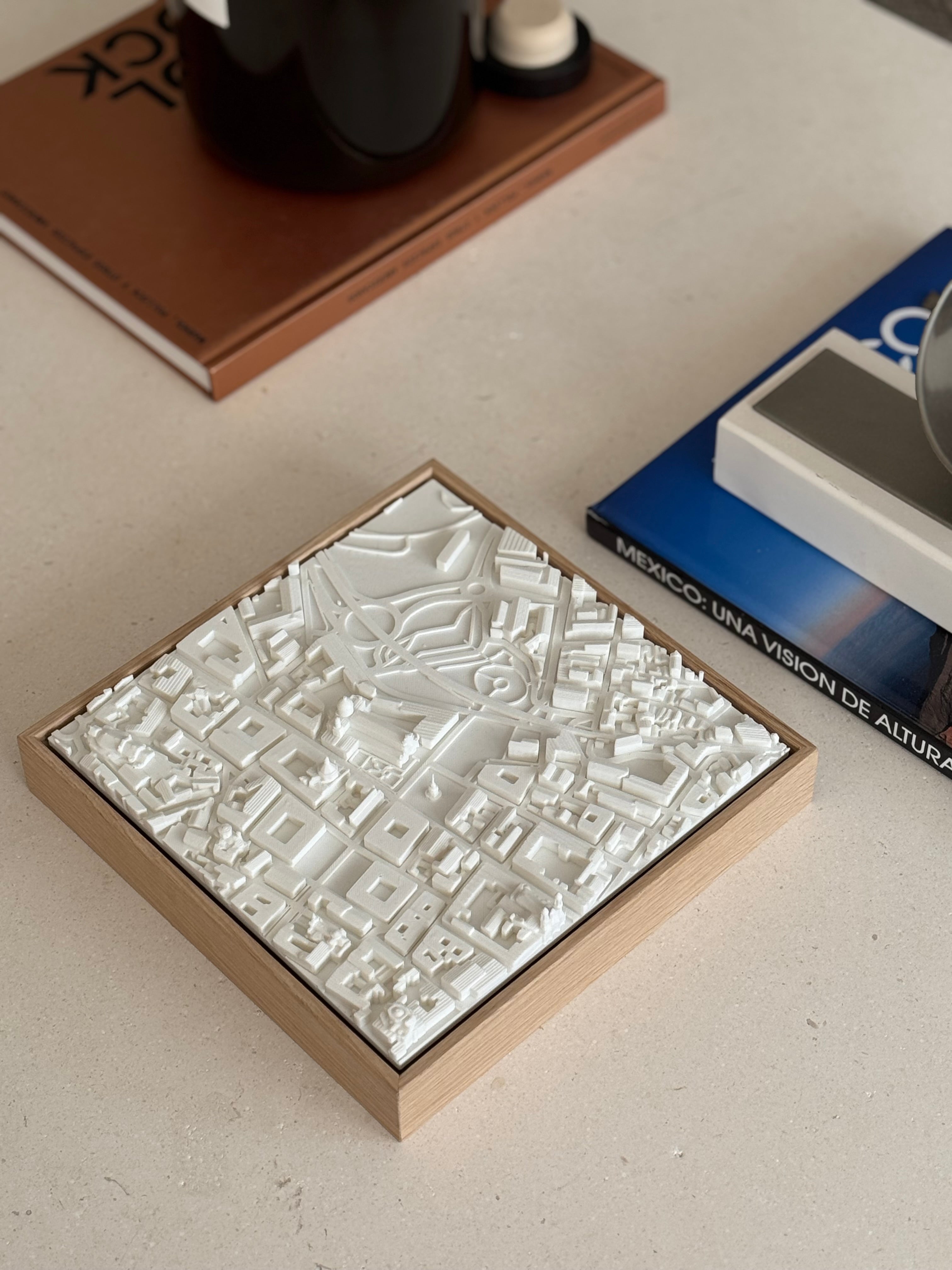 3D city map wall art with white buildings in a wooden frame on a modern table