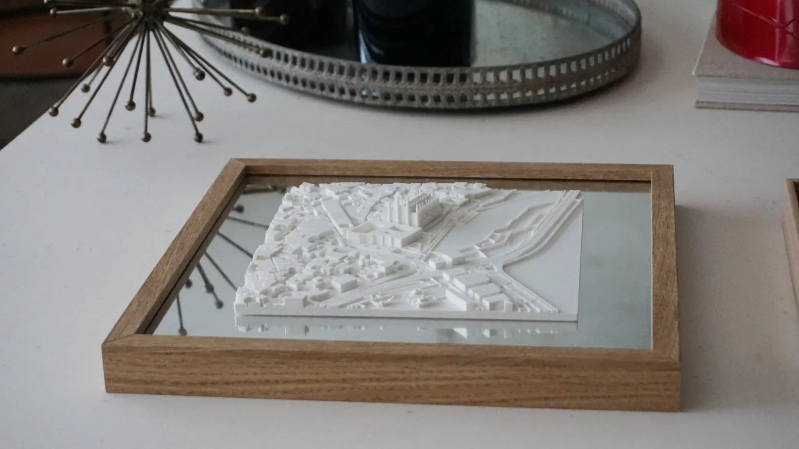 3D city map artwork in wood frame, displayed on a modern white table, home decor