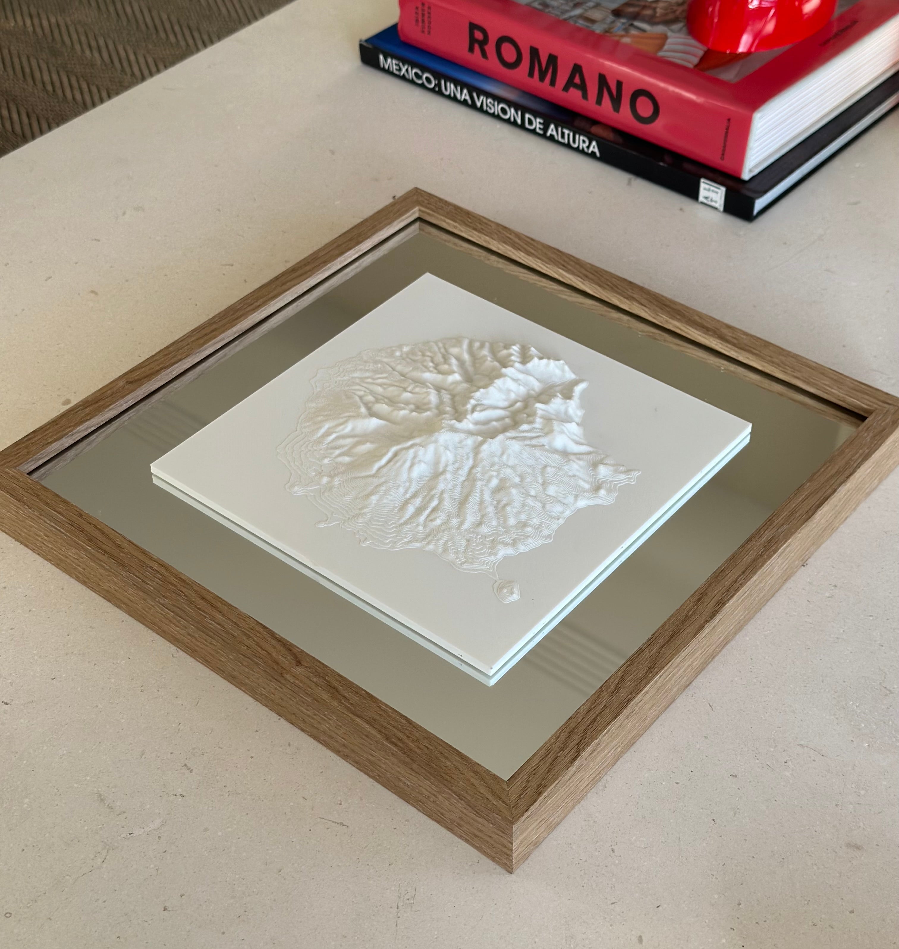Framed 3D city map artwork with raised white topography on a modern table