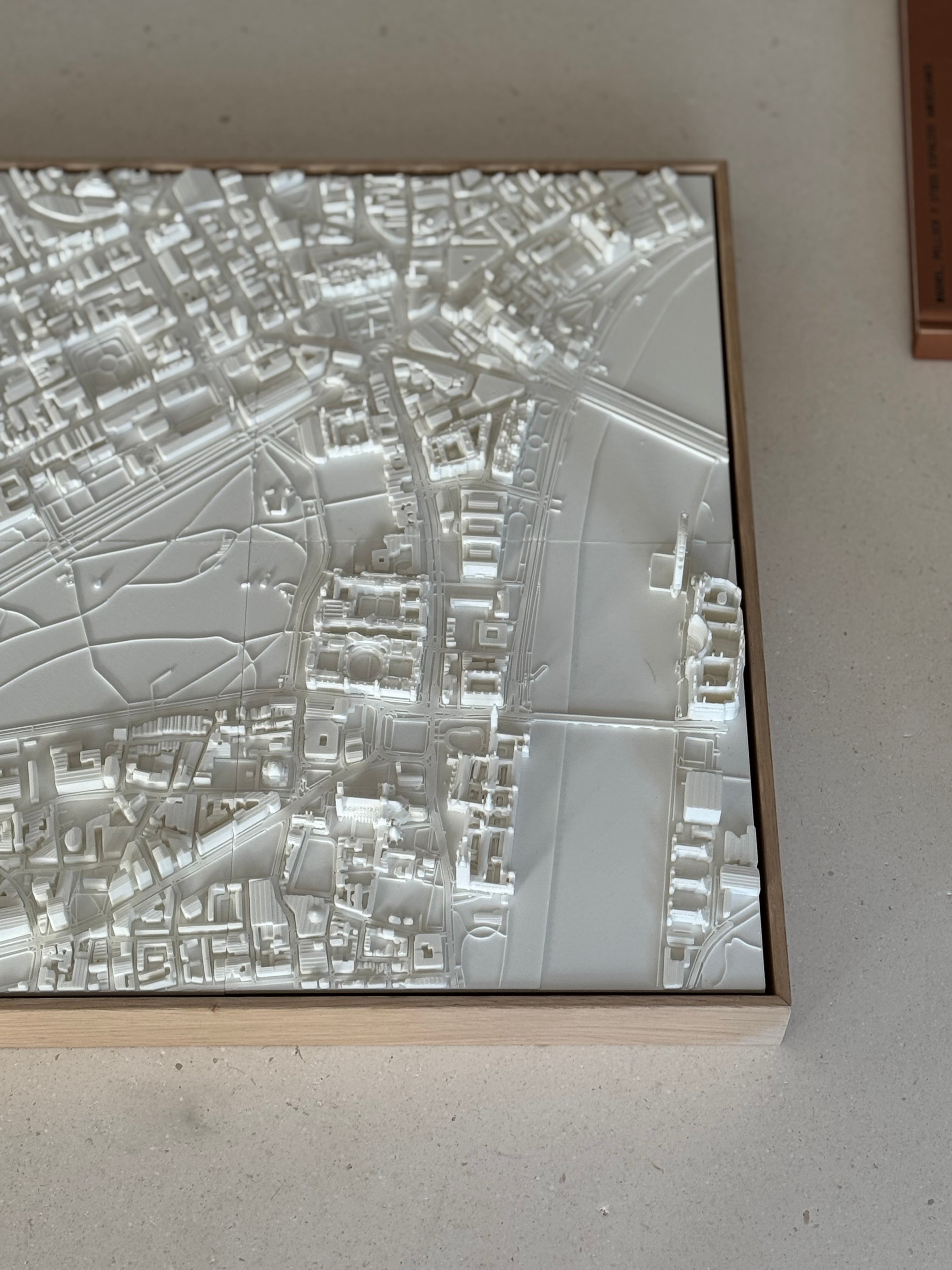Detailed 3D city map wall art in a wooden frame, showing urban streets and buildings.