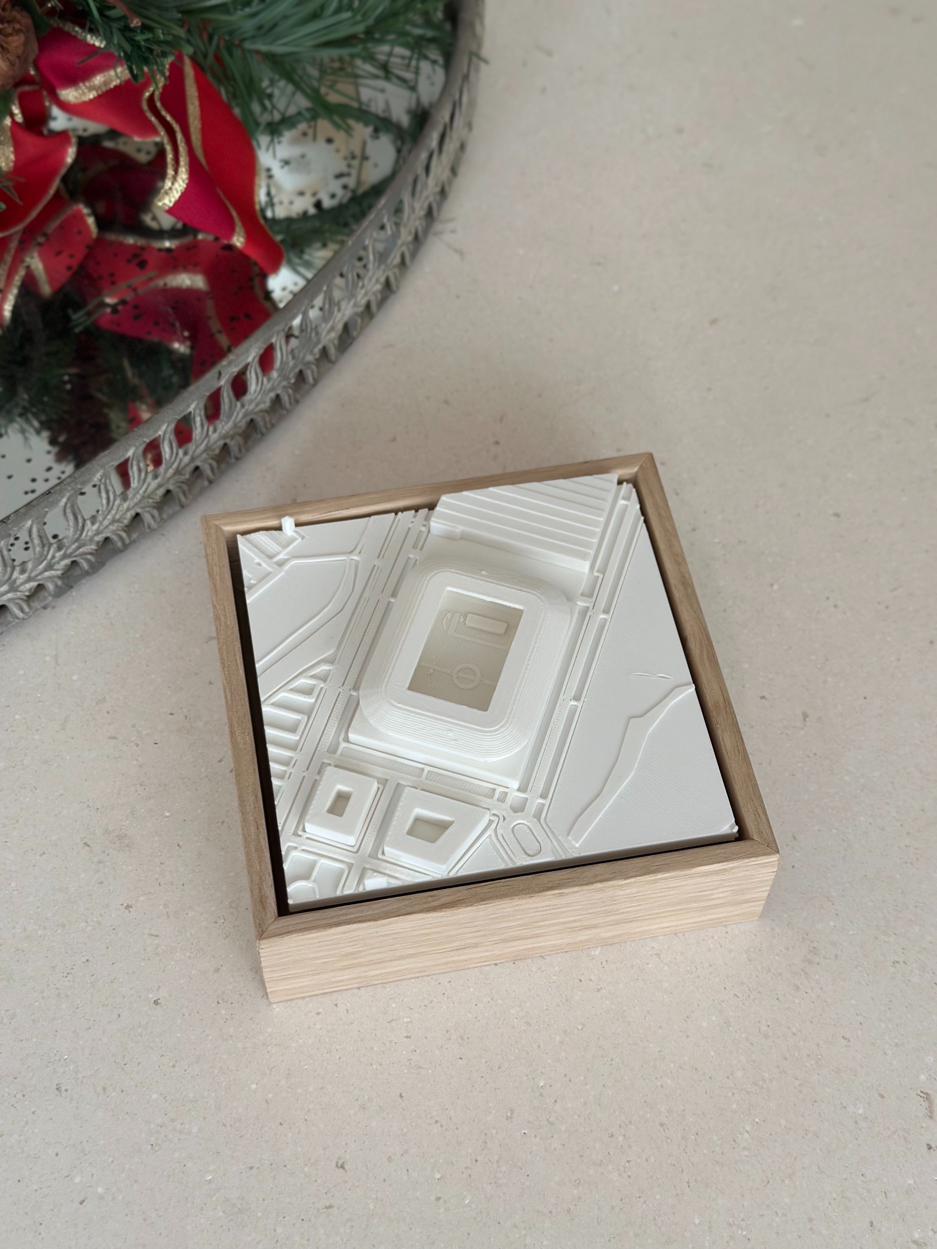 3D city map wall art in wooden frame on beige surface, with holiday decor nearby