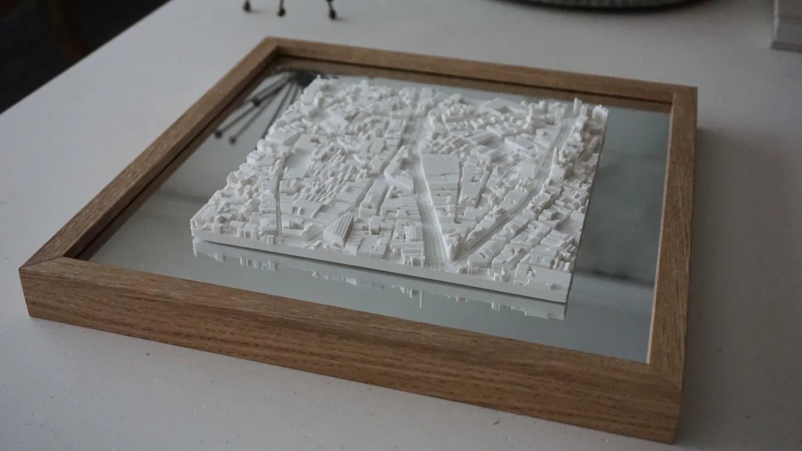 3D city map wall art in a wooden frame on a white surface, modern decor