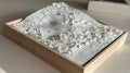 3D city map artwork with topographic details in a wooden frame on a light surface