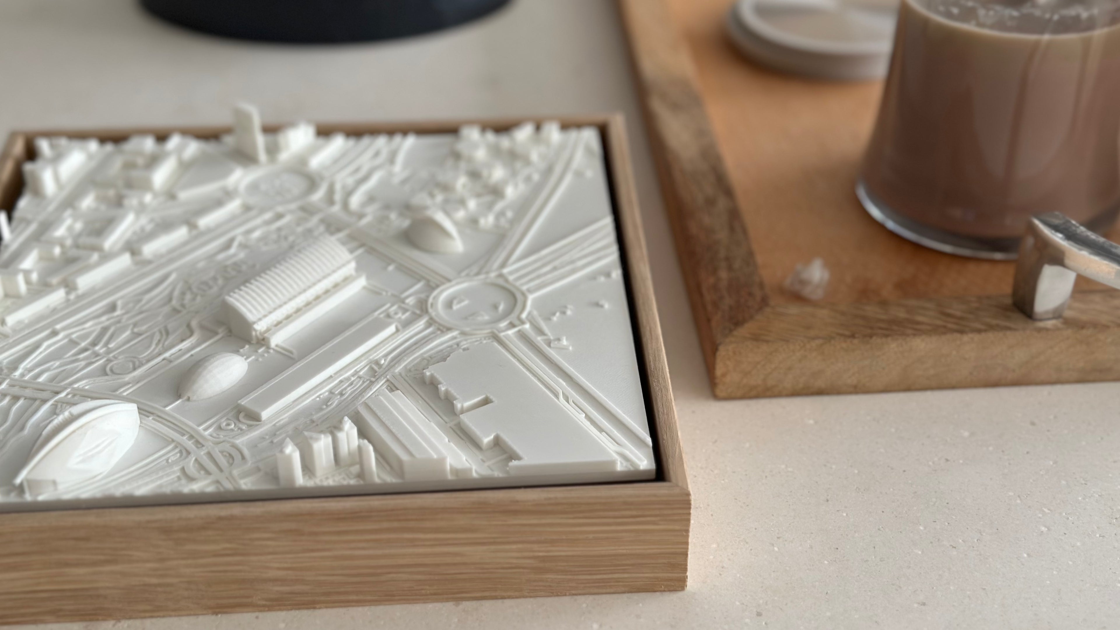 3D city map wall art in white frame on table next to coffee on wooden tray, home decor