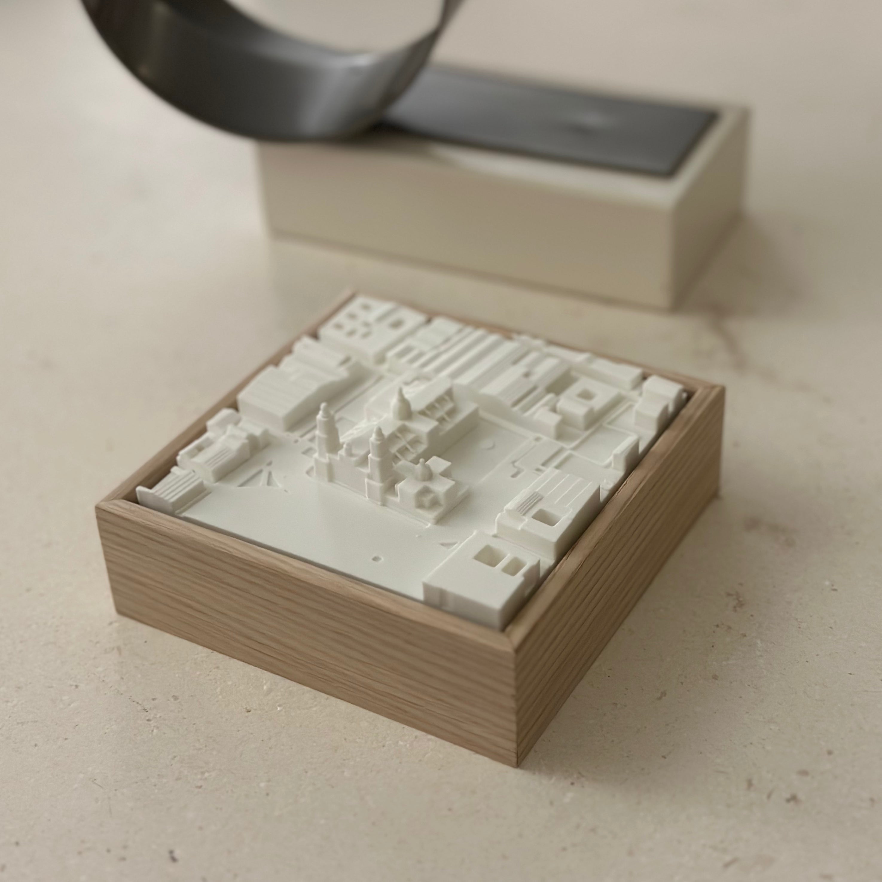 3D city map artwork in a wooden frame on a light surface, modern urban decor