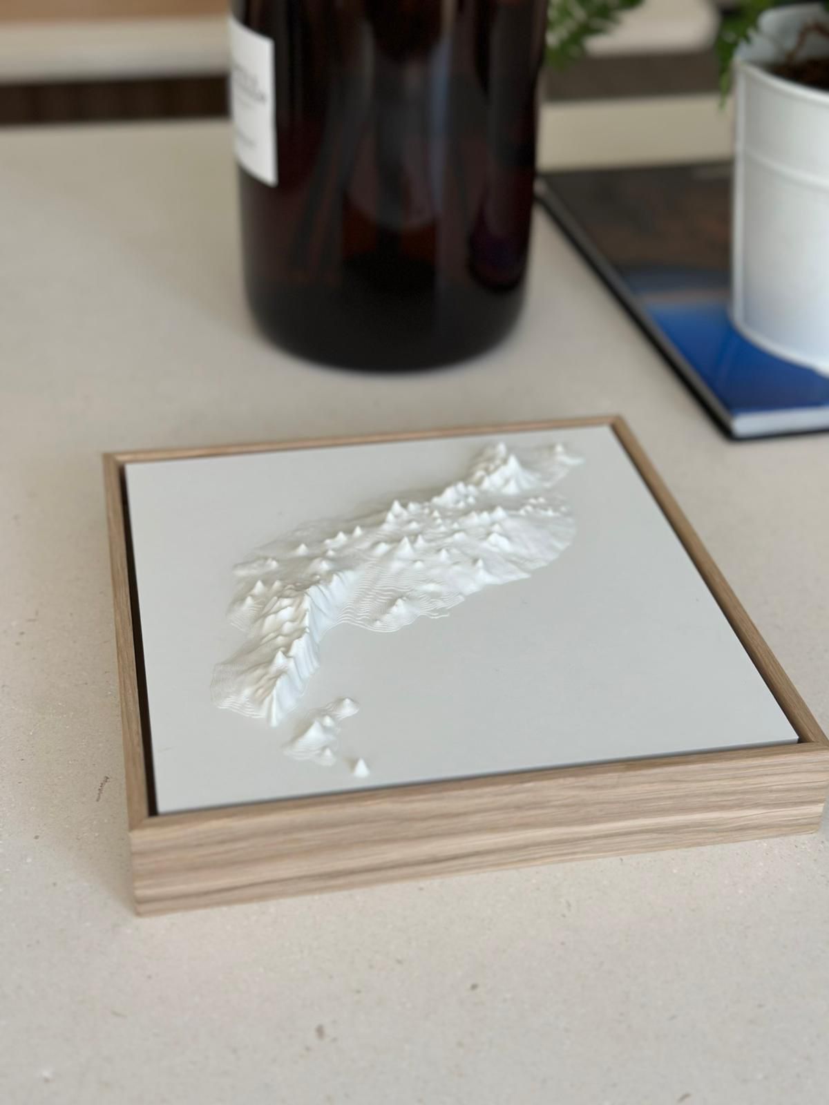 3D relief map of Lanzarote in white, framed with wood, decorative wall art on table.