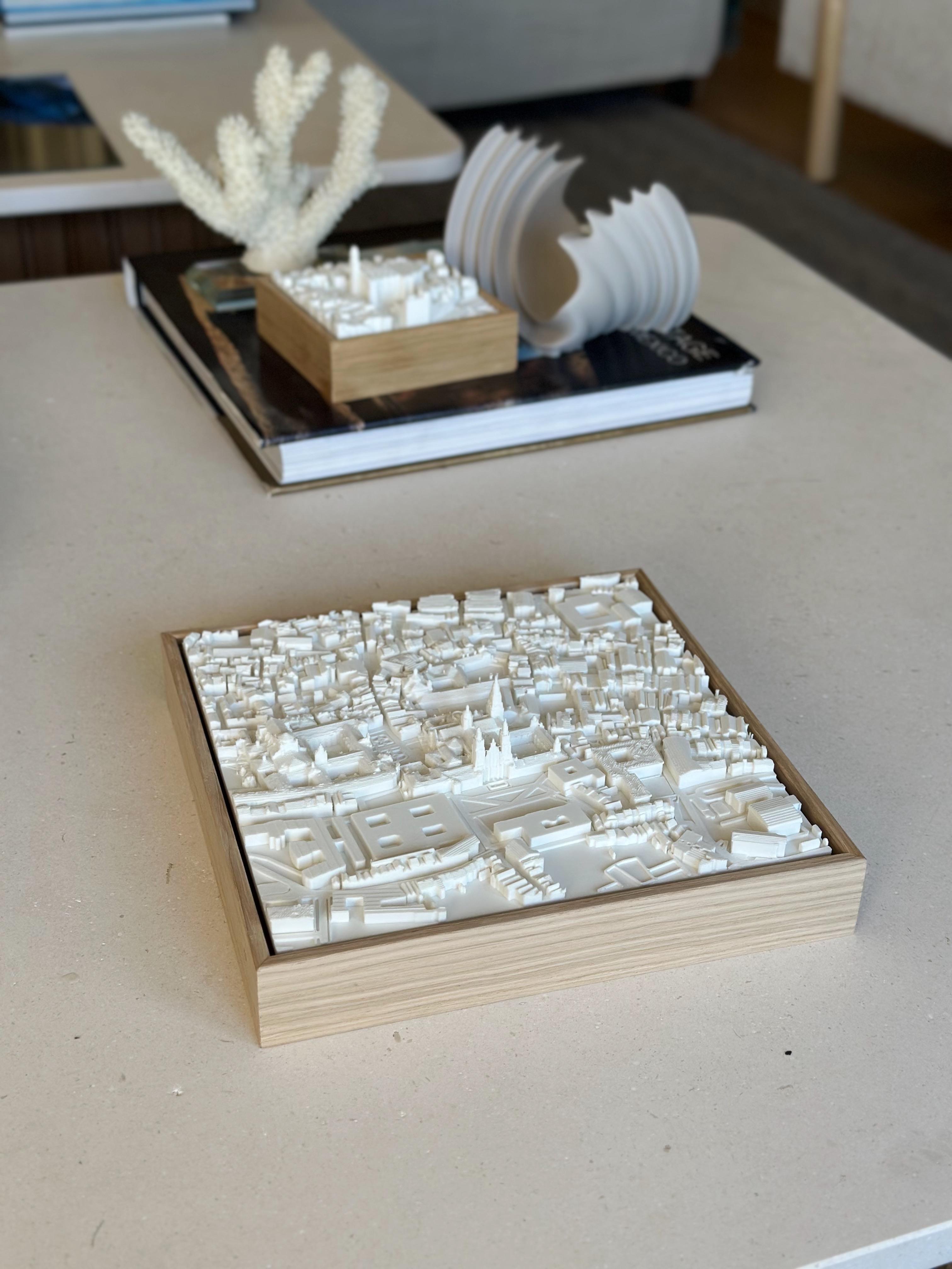 3D city map artwork of Santiago de Compostela in a wooden frame on a modern table